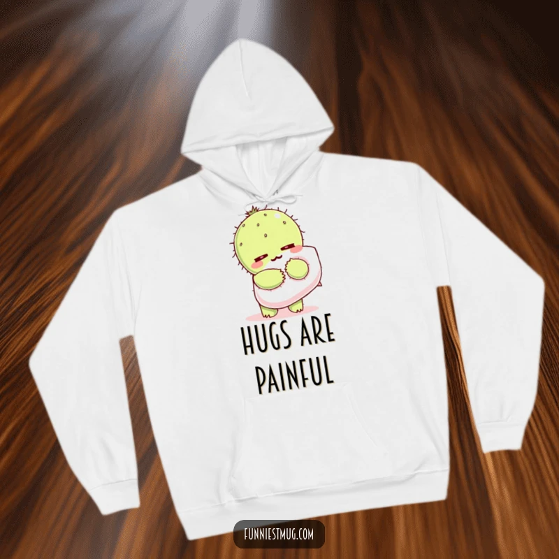 Funny Kawaii hoodie depicting a cactus character wincing while hugging a soft, fluffy pillow.